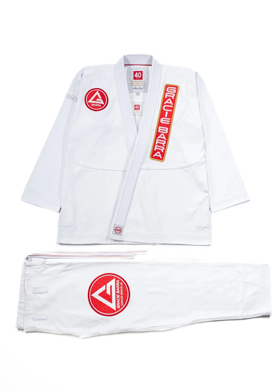 40 Year Anniversary white BJJ kimono flat lay showing jacket and pants with Barra Shield, Gracie Barra Patch, and Legacy G detail