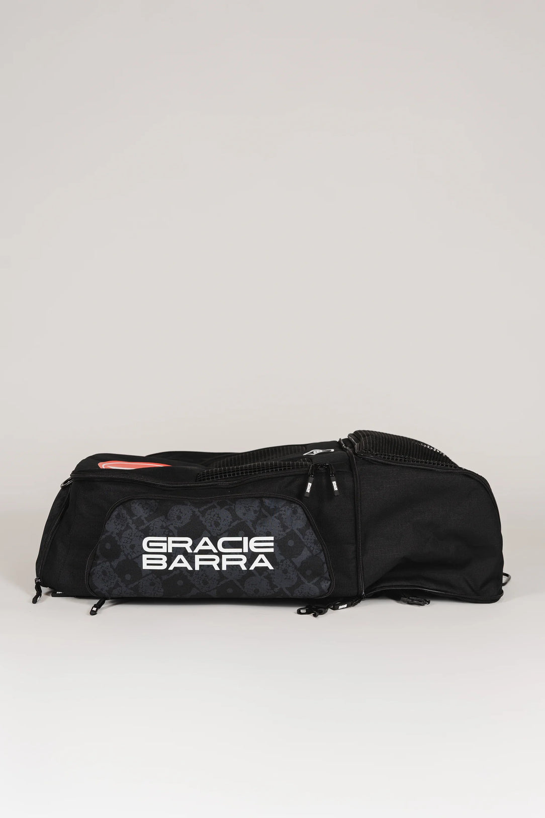 Side view of Black Barra da Tijuca Backpack with lower compartment expanded, showing “Gracie Barra” logo and calçadão pattern panel in duffel configuration.