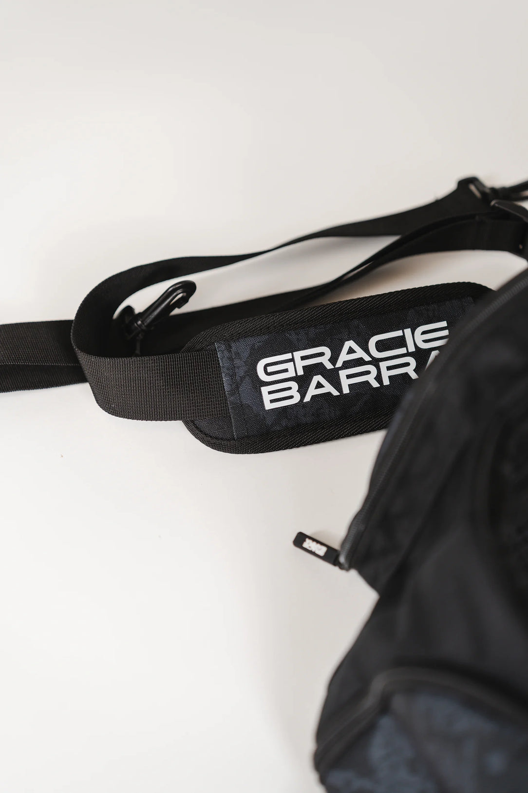 Close-up of Black Barra da Tijuca Backpack duffel strap featuring “Gracie Barra” logo print and adjustable clips for shoulder carry.